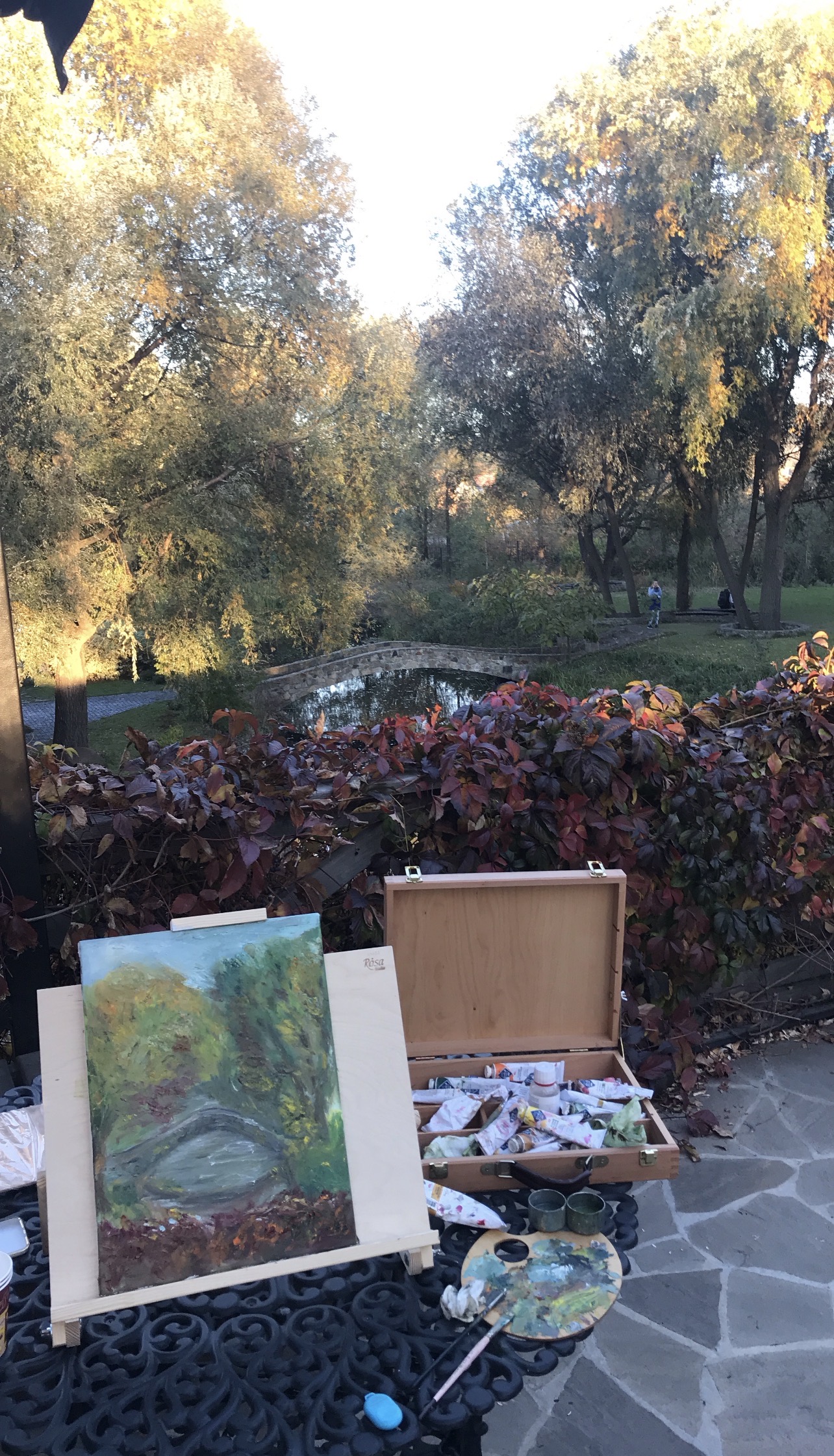 Finished landscape painting by Marina Stognieva displayed in front of the river and bridge at Radomysl Castle